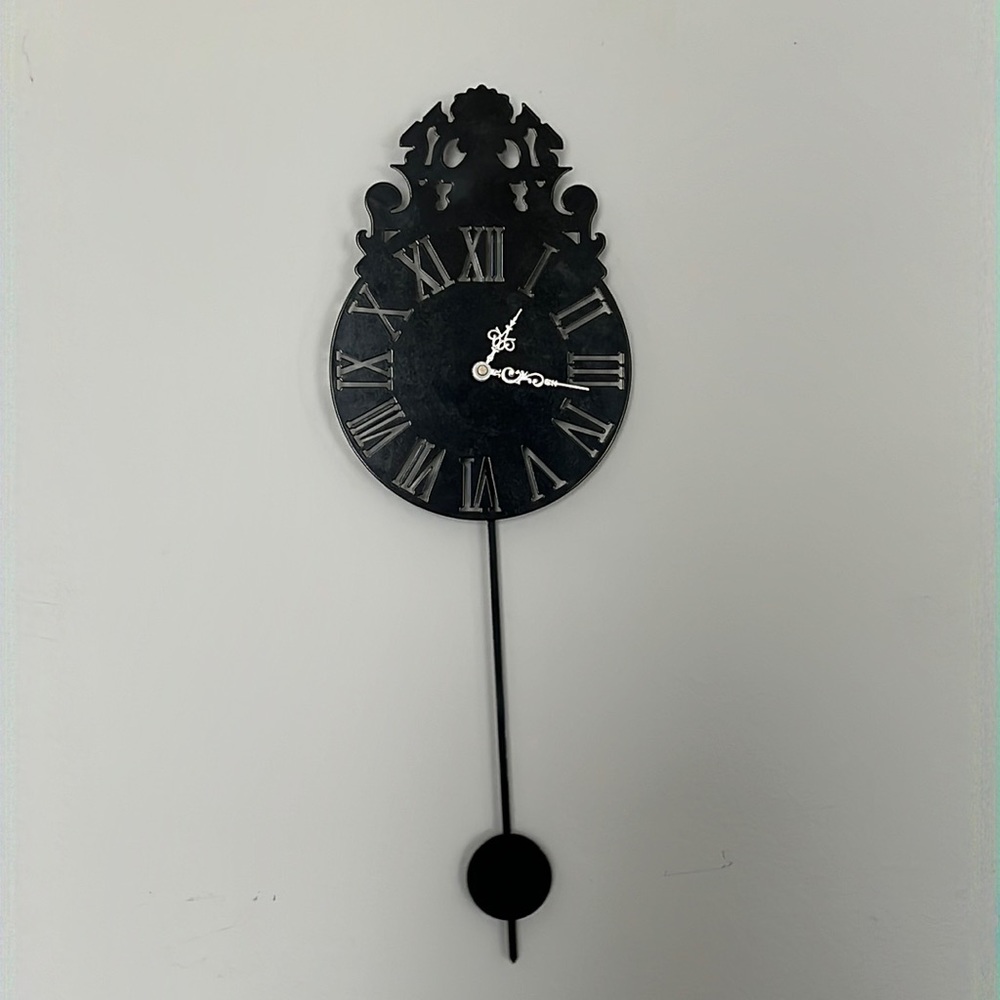 Metal clock with swinging pendulum